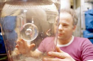 Commander Anatoly Solovyev holds a water dispenser onboard the Base Block of the Mir Space Station during NASA-6. 